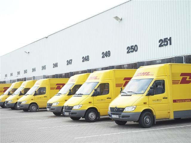 Vehículos de reparto de DHL Express en una plataforma de distribución.