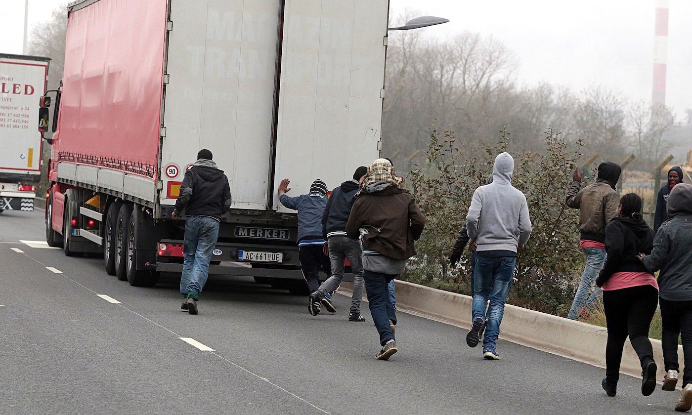 Inmigrantes tratan de subir a un camion en las inmediaciones de Calais