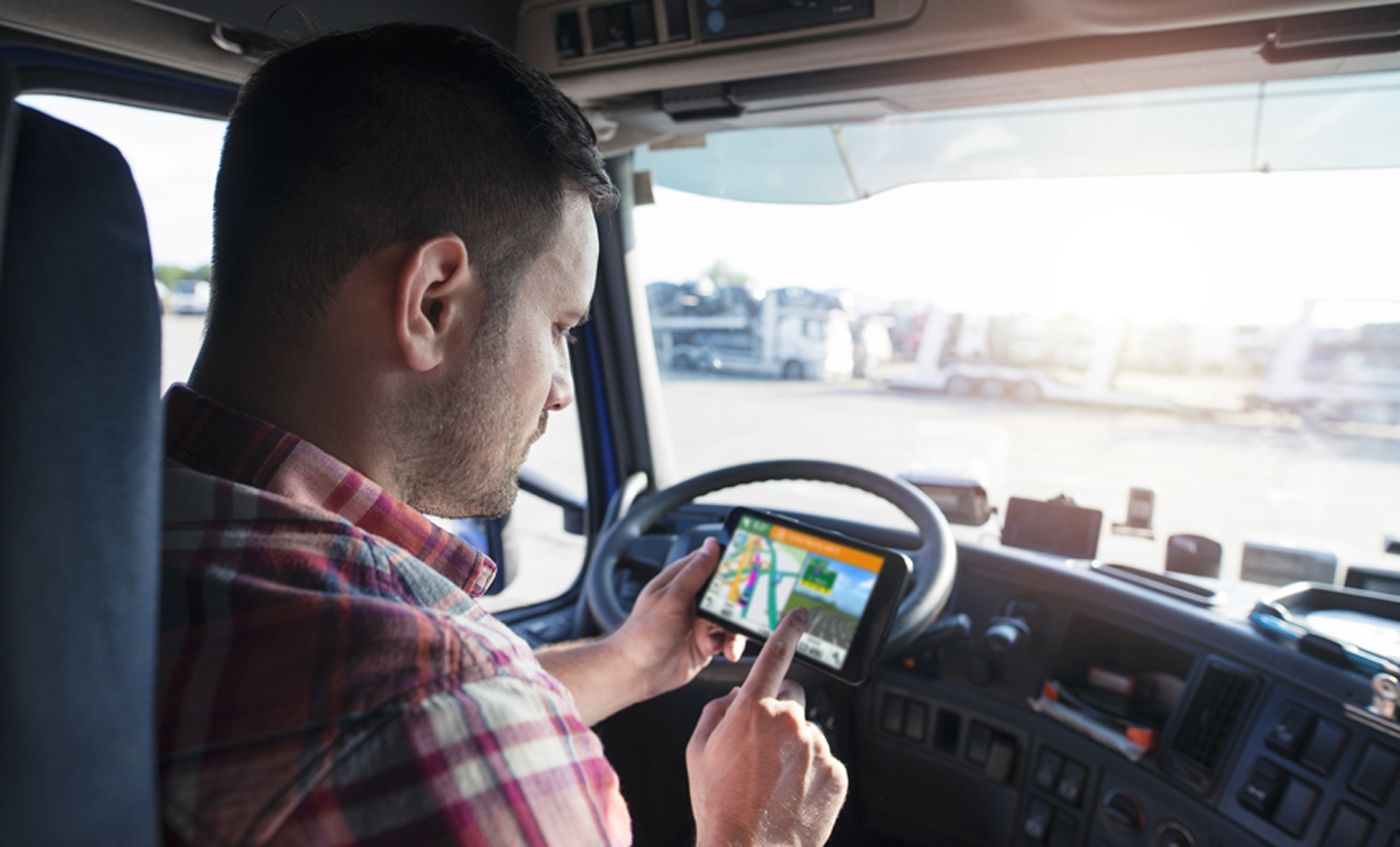 Professional middle aged trucker using truck gps navigation to t