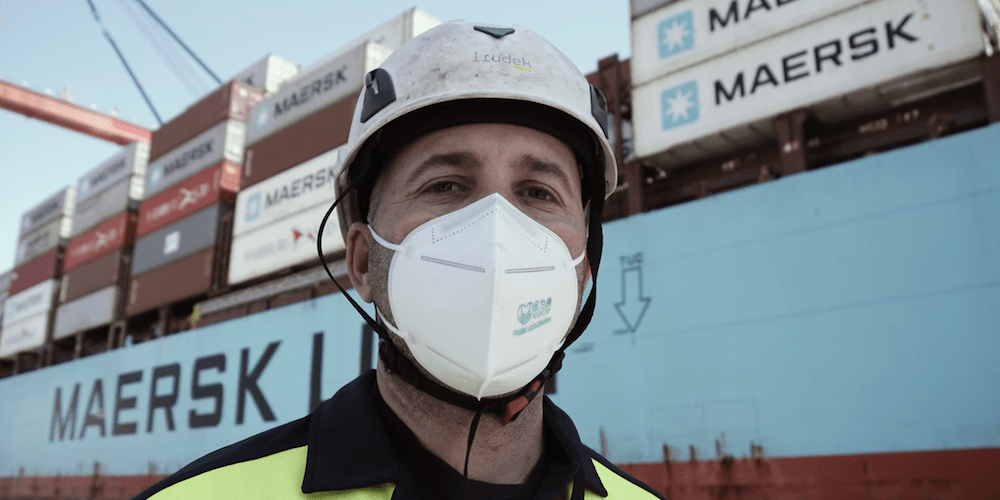 puerto Malaga estibador con mascarilla con portacontenedores Maersk de fondo