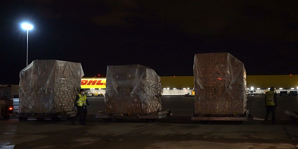 carga aerea tres palets aereo remolcados delante terminal DHL Barajas Madrid nocturna