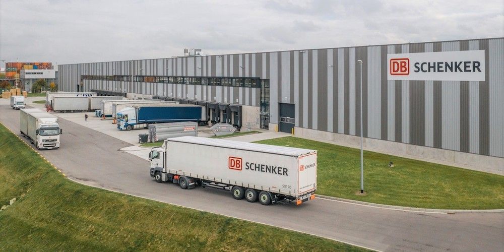 Plataforma logistica de DB Schenker con varios camiones