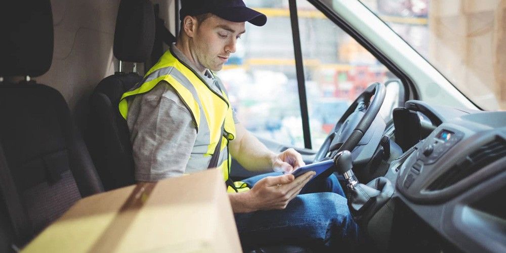 mensajero-con-tablet-en-cabina-furgoneta-entrega-distribucion-last-mile